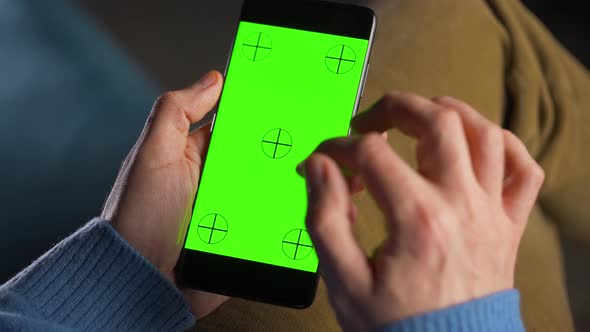 Man Using Smartphone with Green Mockup Screen in Vertical Mode alt