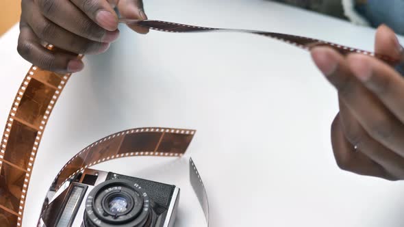 Smiling African American Guy Looks at Photographic Film alt