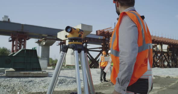 Male Surveyors Using Theodolite Together alt