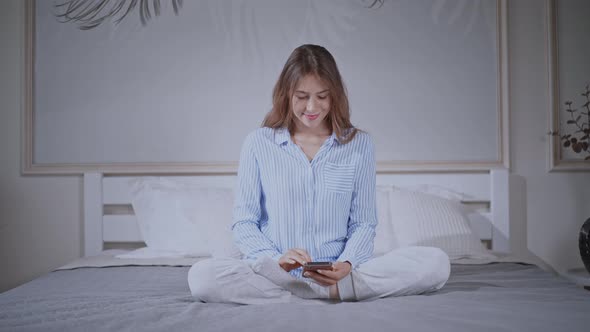 Female Typing Message on Mobile in Bedroom