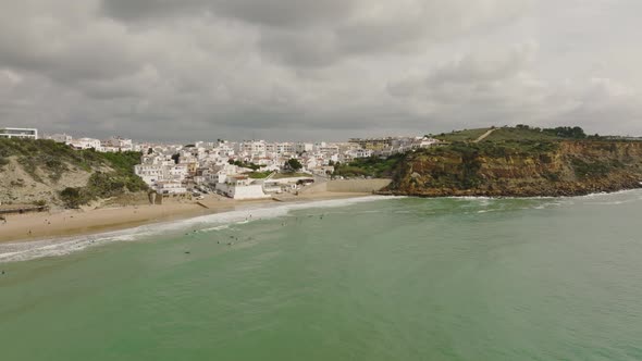 Aerial shot of surfers waiting for waves at a beach along the Atlantic Ocean in Portugal underneath alt