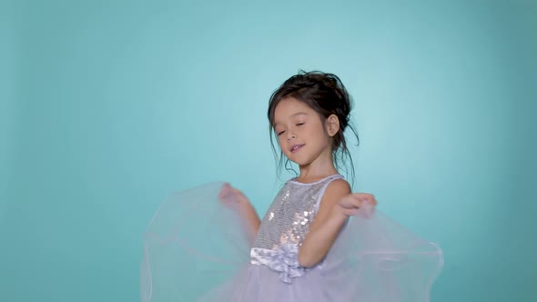 Beautiful Little Child Girl in Silver Dress Dancing on Blue Background