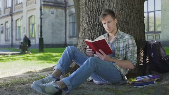 Young Man Reading Book with Fascinating Storyline Empathizing with Characters alt