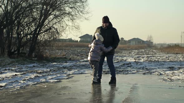 Dad and Daughter 78 Years Old are Walking on the Ice of a Frozen Reservoir