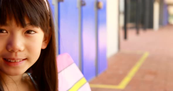 Portrait of happy schoolgirl sitting in locker room 4k alt