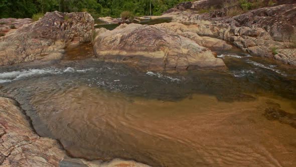 View of Transparent Pool Among Rocks Against Green Hills alt