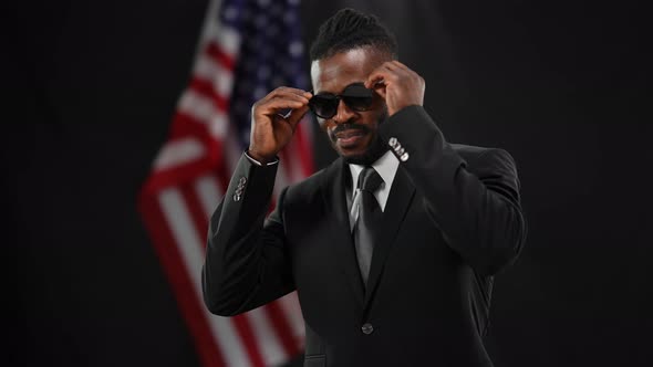 Successful Handsome Confident African American Man in Formal Suit Putting on Sunglasses Dancing in alt