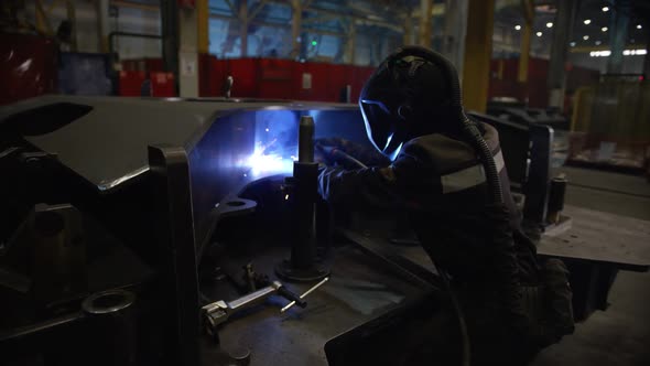 A Welder is Working in the Factory Shop