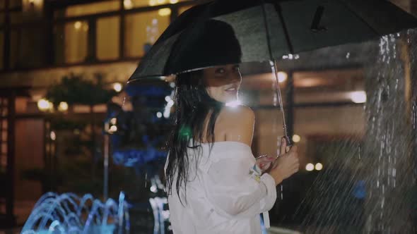 Wet Brunette Walks with Umbrella Under Rain and Smiles at Camera alt