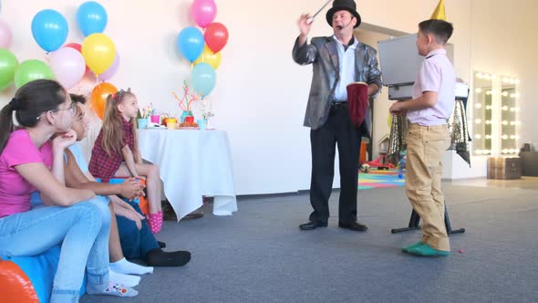 Performer in Silver Jacket Shows Magic Tricks at Party alt