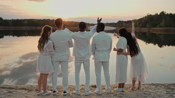 Group of Friends Hugging at the Beach Party Looking at the Sunset