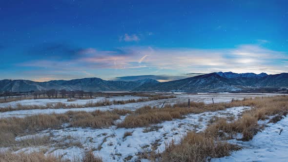 Wide angle cinemagraph of a peaceful mountain scene with an animated sky and snow gently falling in alt