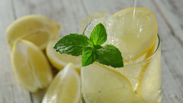 Soda Is Poured Into A Glass With An Iced Lemon Drink And Fresh Mint.