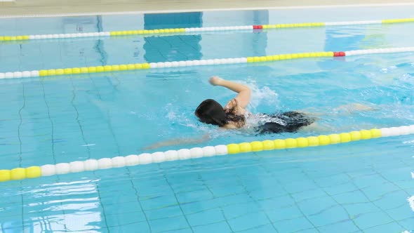 Young caucasian athletic woman female swimmer in one-piece swimsuit swimming alone in large indoor p alt
