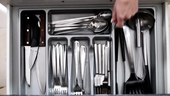 Young girl in the kitchen with a set of silver cutlery cutlery