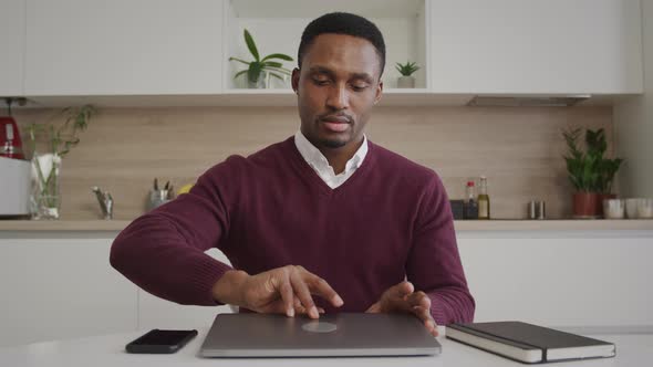 Young Black 20s Adult Man Walks in the Frame Opens the Laptop and Gets to Work alt