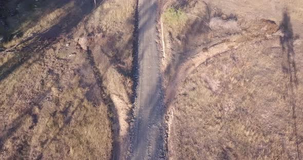 Aerial flight over a road in Australia with surrounding grassland, birds eye perspective moving forw alt
