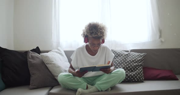 Latin American Woman with Afro Hair Sitting on the Sofa at Home Reading a Book alt