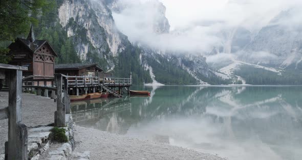 Small Boathouse with Wood Pier and Boats on Braies Lake with Cloudy Weather