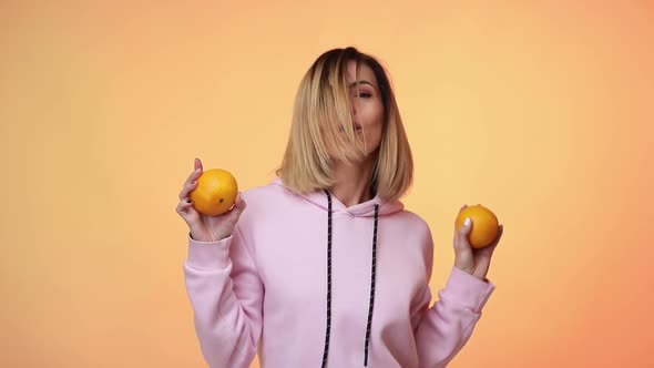 Woman in Casual Pink Clothes Holding Oranges and Dancing
