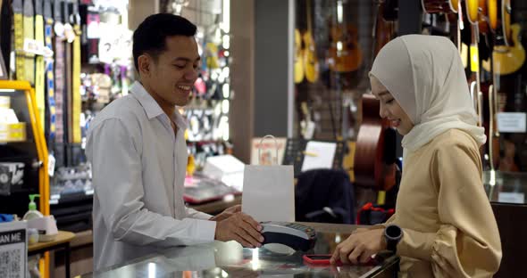 Young muslim woman use smartwatch paying over contactless transactiona at cashier counter 
