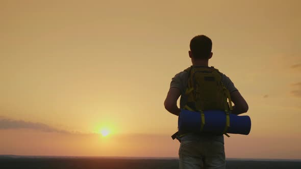 A Young Male Tourist with a Backpack Looks at the Horizon alt