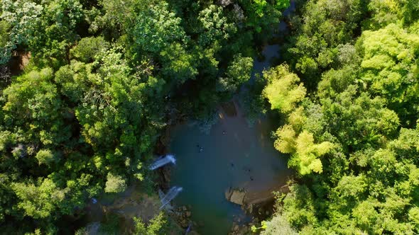 Waterfall plunges into freshwater pool in middle of jungle; drone top down alt