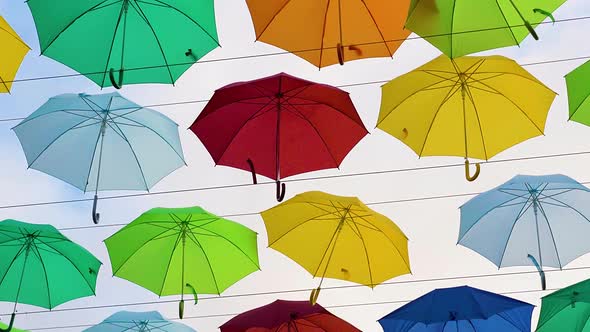 Flying Umbrellas. Multi Colored Parasol Soar in the Sky. Umbrellas Suspended Above Their Heads alt