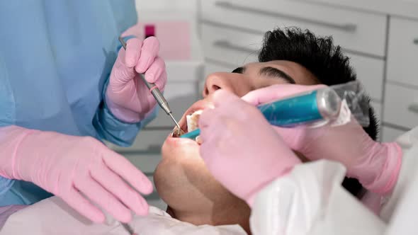 Close Up of Dentist Using Dental Curing UV Lamp on Teeth of Patient alt