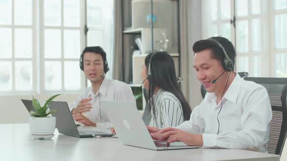 A Man Of Three Asian Call Centre Agents Speaking To Customer While His Colleagues Are Talking alt
