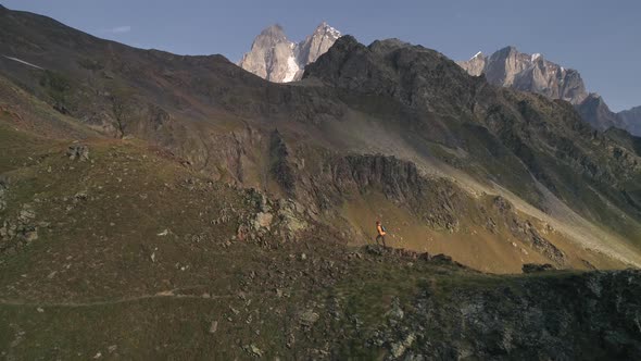 Aerial Shot of a Man Climbing Mountains on a Sunny Day in Autumn