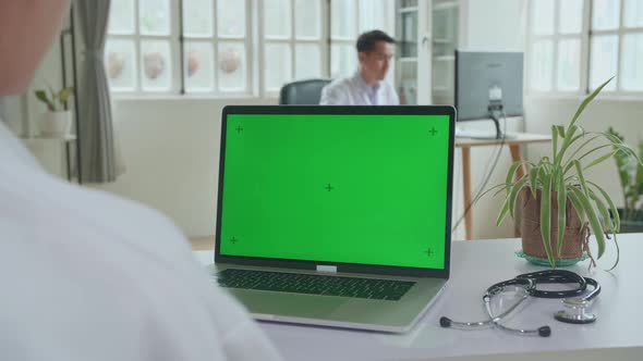 Close Up Asian Woman Doctor Having Video Conference On Laptop With Mock Up Green Screen Display alt