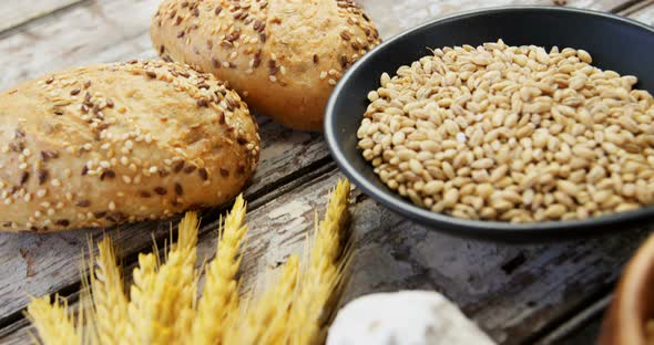Wheat grains with bread buns, oats and spoon full of flour alt