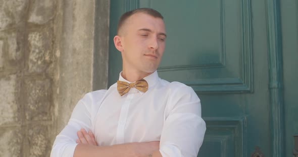 Handsome man in suit or groom standing against green door in old town in Montenegro. alt
