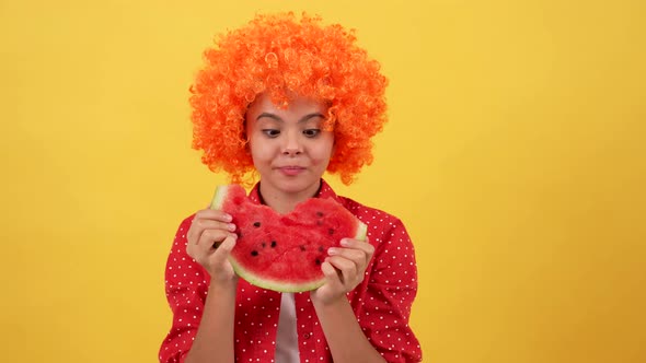 Happy Hungry Teen Girl in Orange Hair Wig Showing Tongue and Biting Water Melon Slice Summer alt