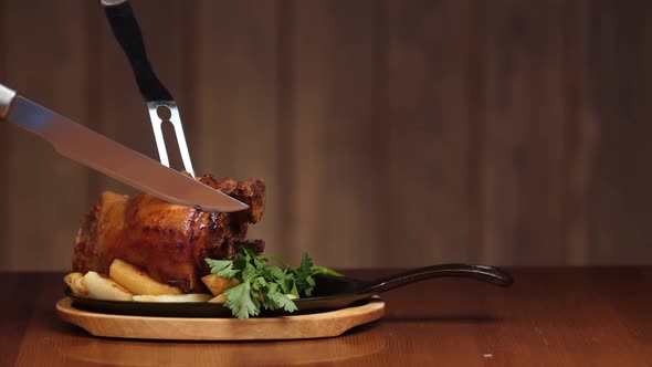 Cut Off a Large Piece of Meat From the Pork Knuckle with a Knife. Ready Meat Dish with Garnish in a