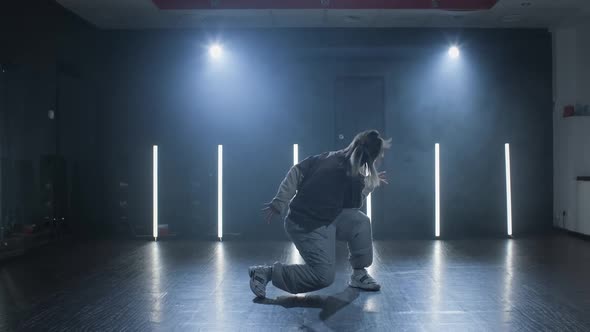 Young Woman Perfrorming Hiphop Dance on Stage with Smoke on Background alt