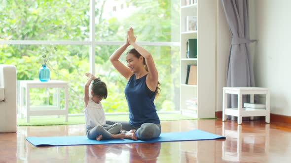 Young mother is teaching basic yoga postures for daughter