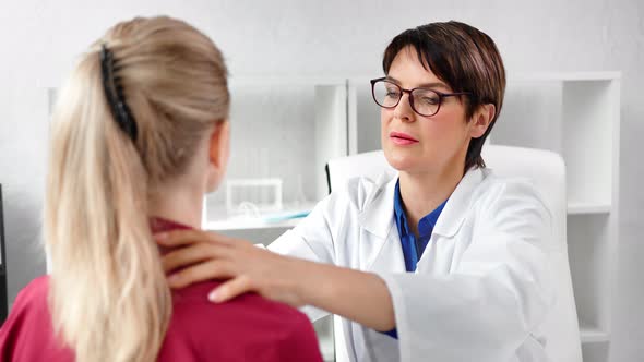 Focused Mature Female Doctor Checking Thyroid Gland of Girl Patient Touching Neck Medium Closeup alt