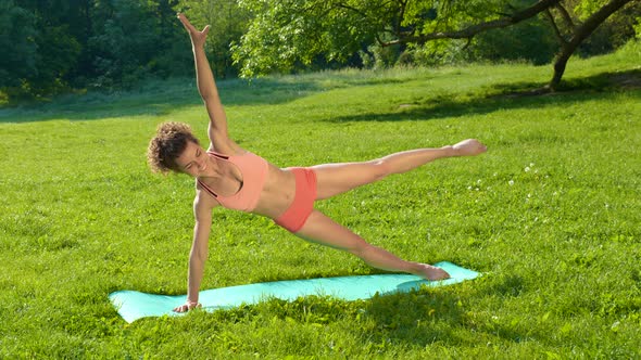 Young Beautiful Girl Doing Fitness Workout on the Grass in the Park alt