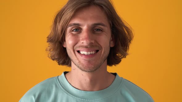 Smiling blond man opening eyes at the camera alt