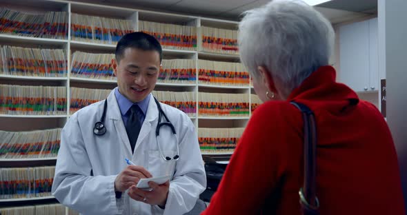 Young Asian male doctor prescribing medicines for patient in clinic 4k alt