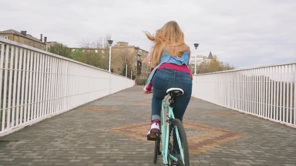 A Young Hipster Girl Riding a Fixed Gear Bike at City Centre Slow Motion alt