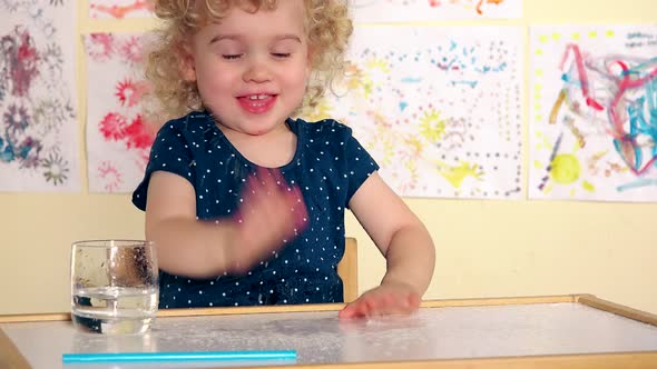 Funny Girl Child Pour Water on Table and Spatter It with Palms