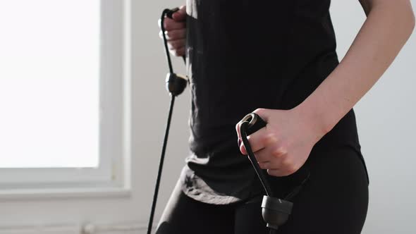 Woman in a Black Sportswear Doing Exercises Using Expander on the Stepper alt