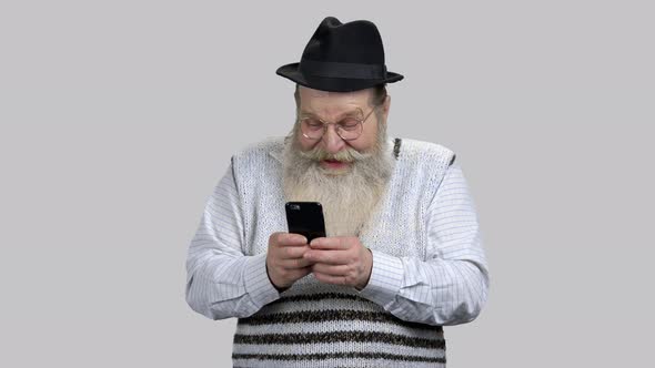 Old Aged Man Having Fun Online with His Smartphone alt