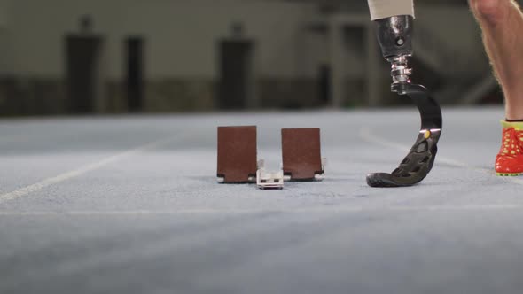 Low section of caucasian disabled male athlete with prosthetic leg getting ready to start a run alt
