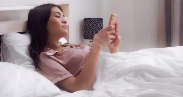 Woman Enjoys the Good News Read in the Phone Lying on the Bed