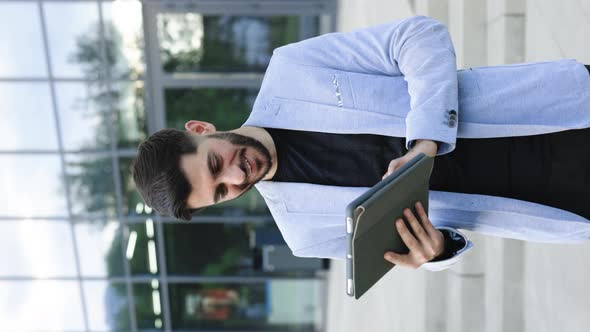Vertical Screen of Businessman Holding Tablet in Hands Using Business Apps on Tablet Computer