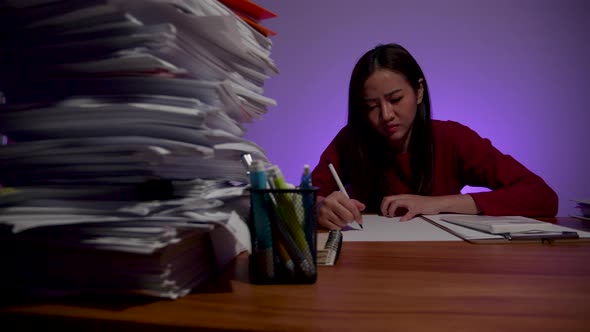 Tired Asian woman doing overtime at home office, late time business. Workaholic people concept
